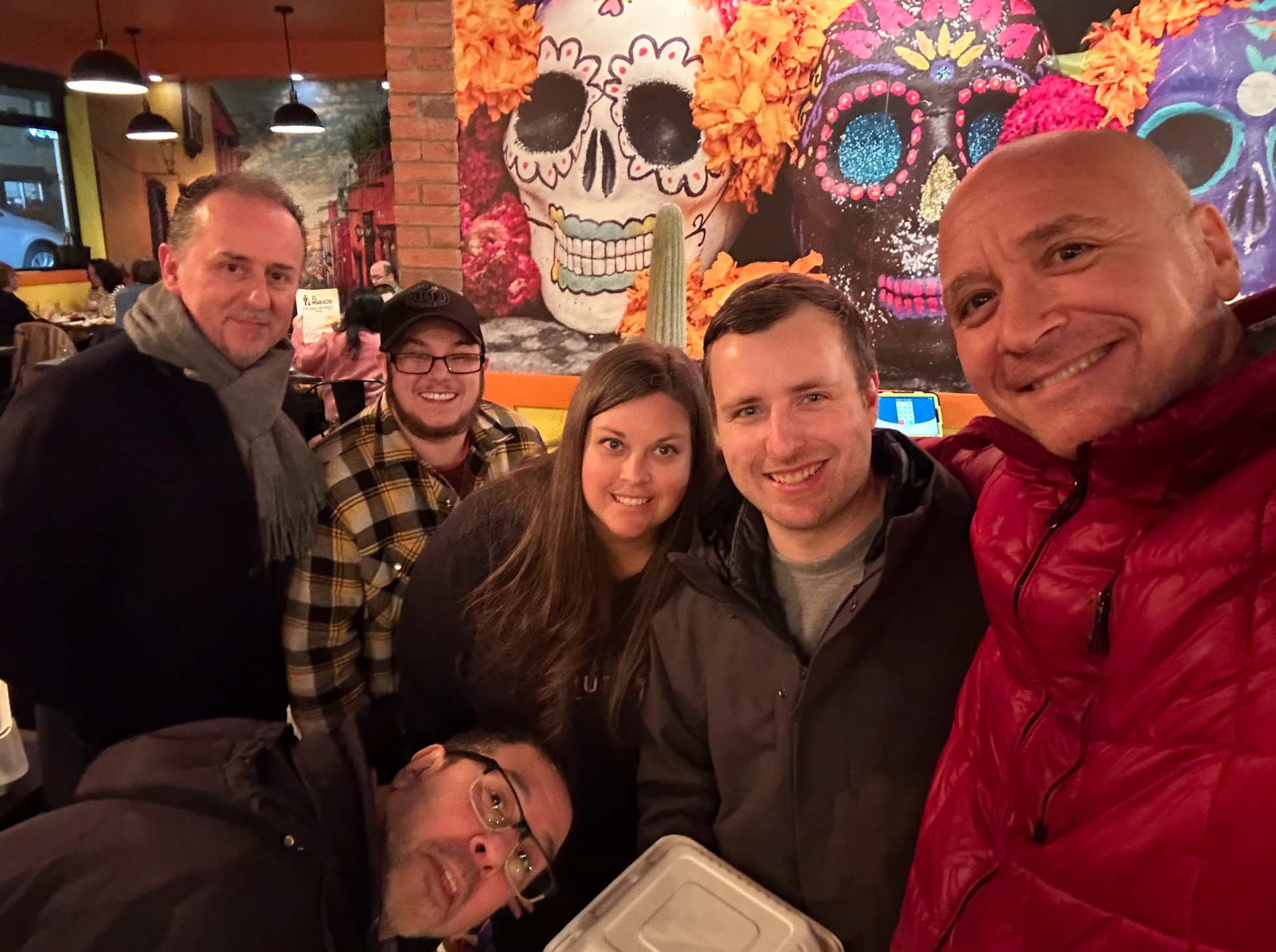 A group of people are posing for a picture in front of a wall with a skull on it.