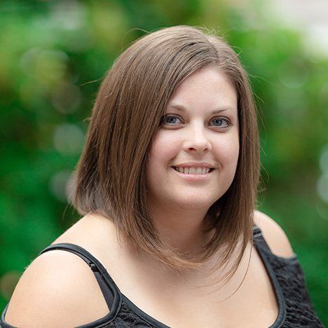 A woman with brown hair and blue eyes is smiling for the camera.