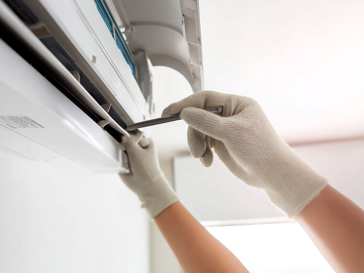 Hands in gloves servicing an air conditioning unit.