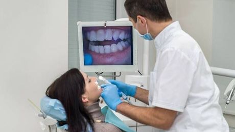 a dentist is examining a woman 's teeth in a dental office .