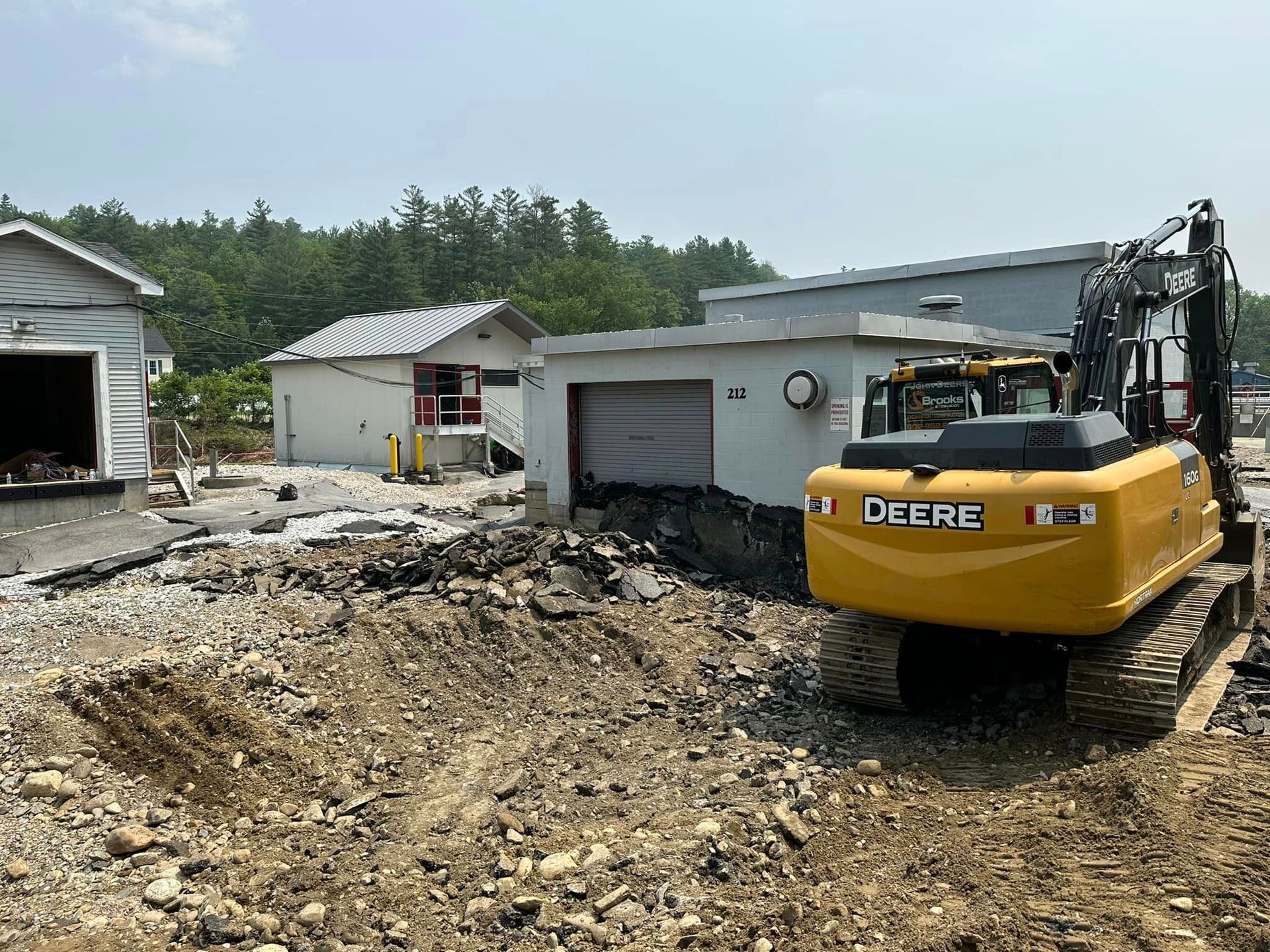 A yellow excavator is sitting in the dirt in front of a house.
