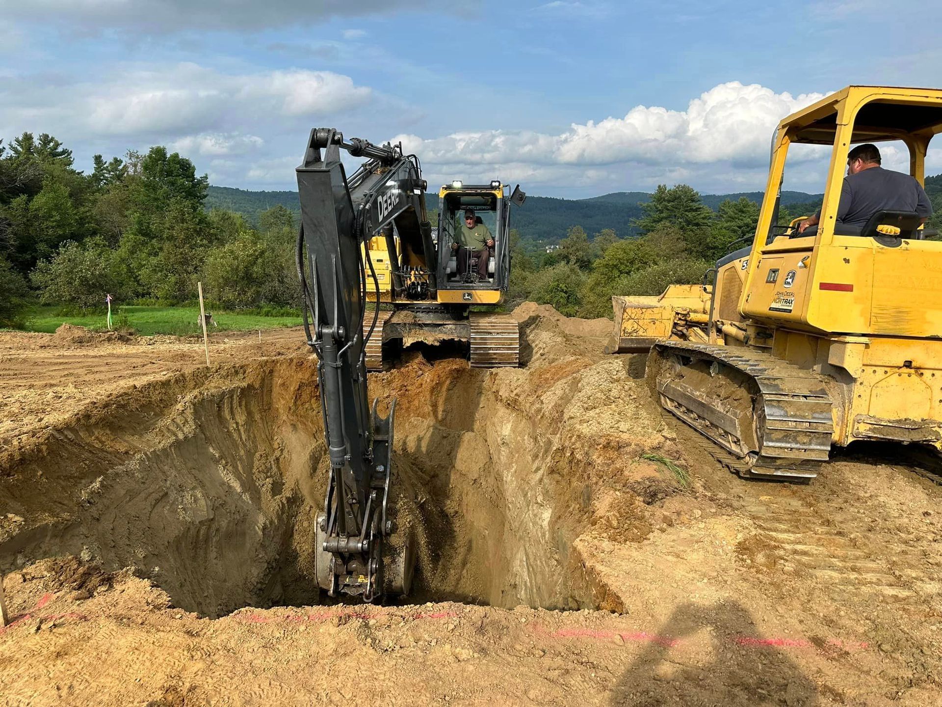 Two bulldozers are digging a hole in the ground.