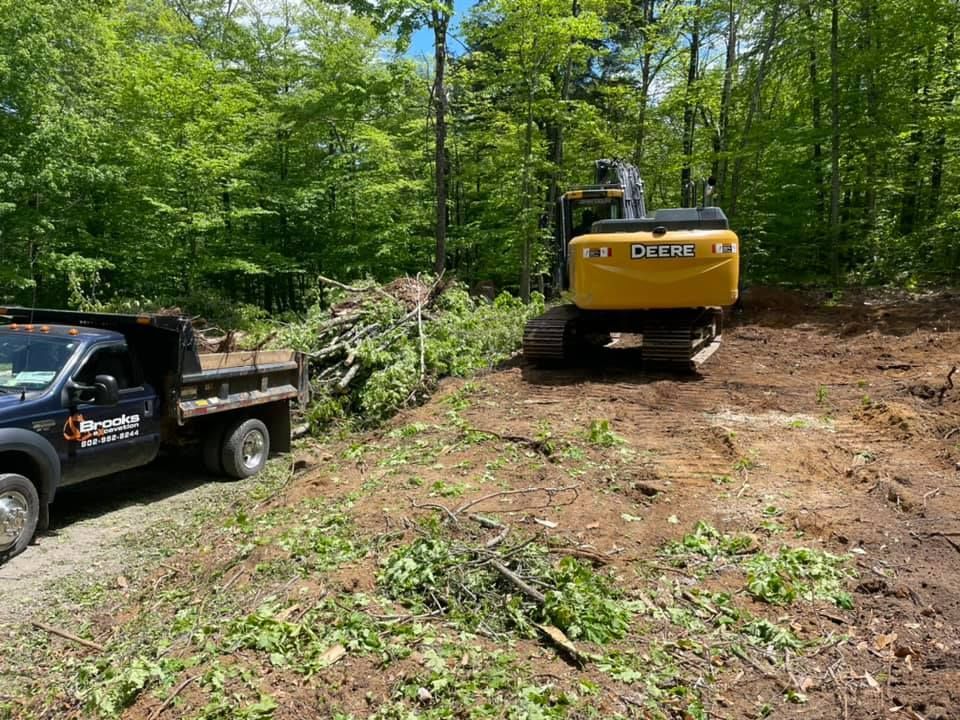 A dump truck is parked next to a bulldozer in a dirt field.