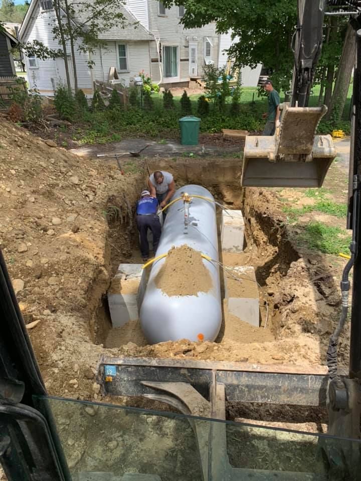 A propane tank is being installed in a hole in the ground.