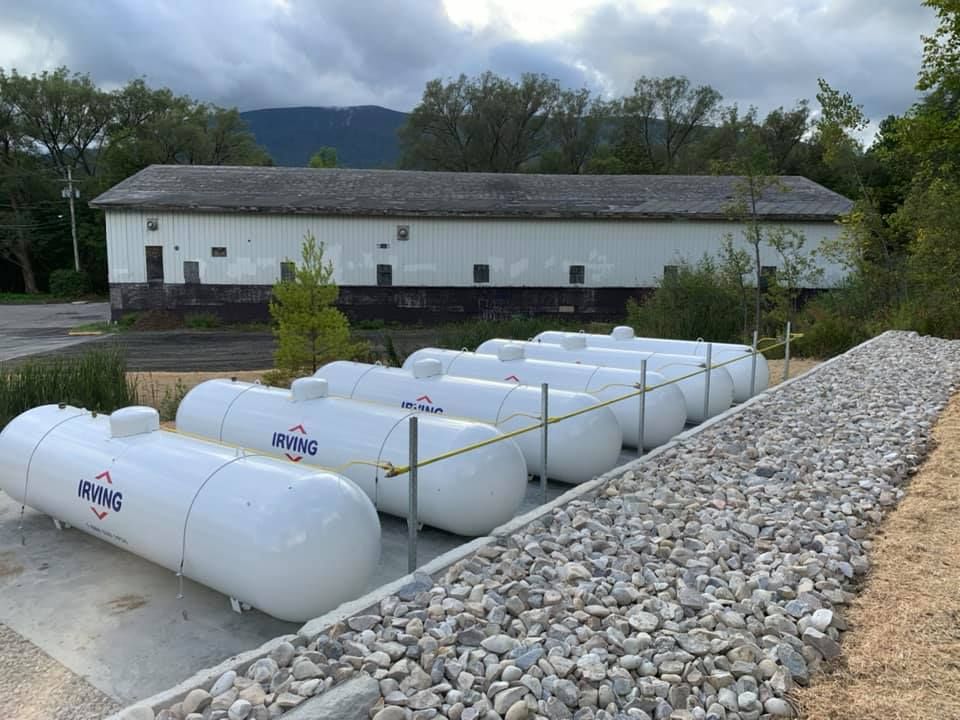 A row of propane tanks are lined up in front of a building.