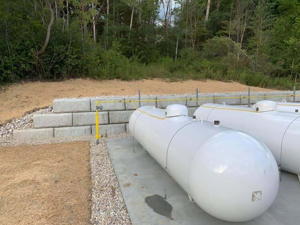 A row of propane tanks are sitting next to each other in a field.