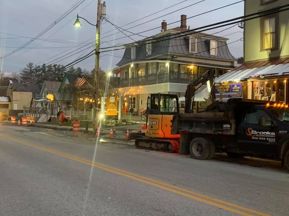A dump truck is parked on the side of the road in front of a building.