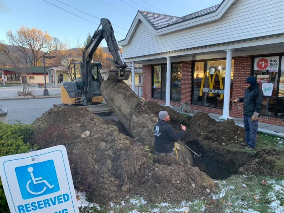 A man is digging a hole in front of a mcdonald 's restaurant.