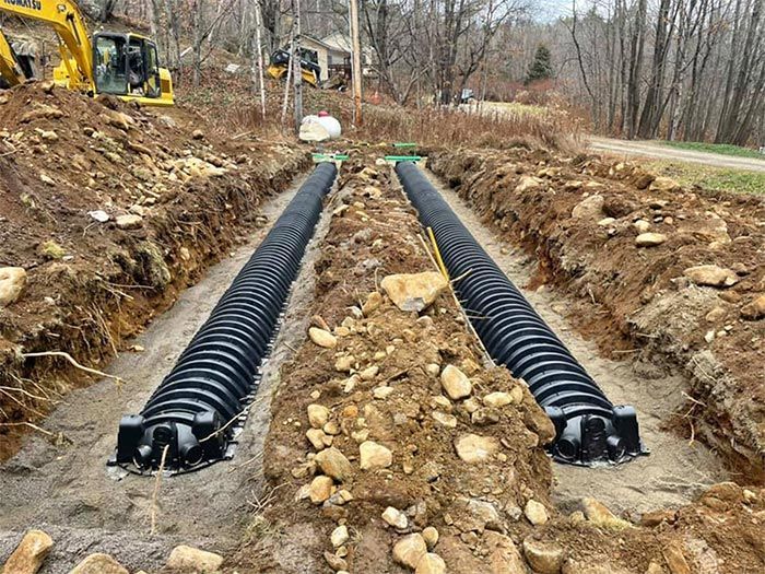 A drainage system is being installed in a dirt field.
