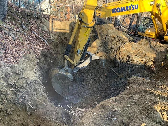 A yellow komatsu excavator is digging a hole in the ground.