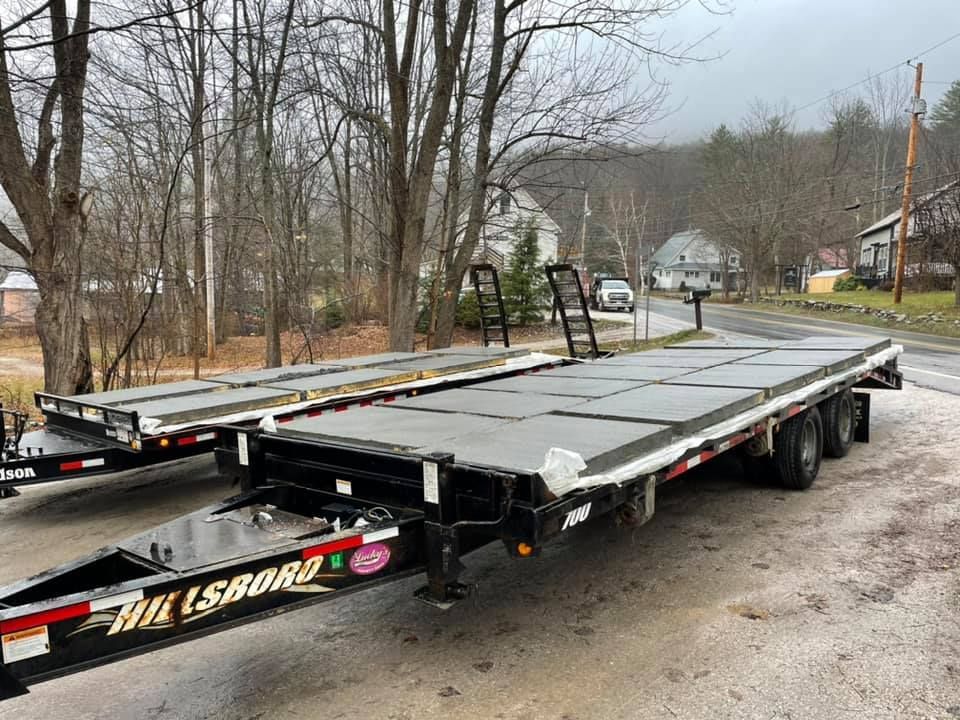 Two trailers are parked next to each other on the side of the road.
