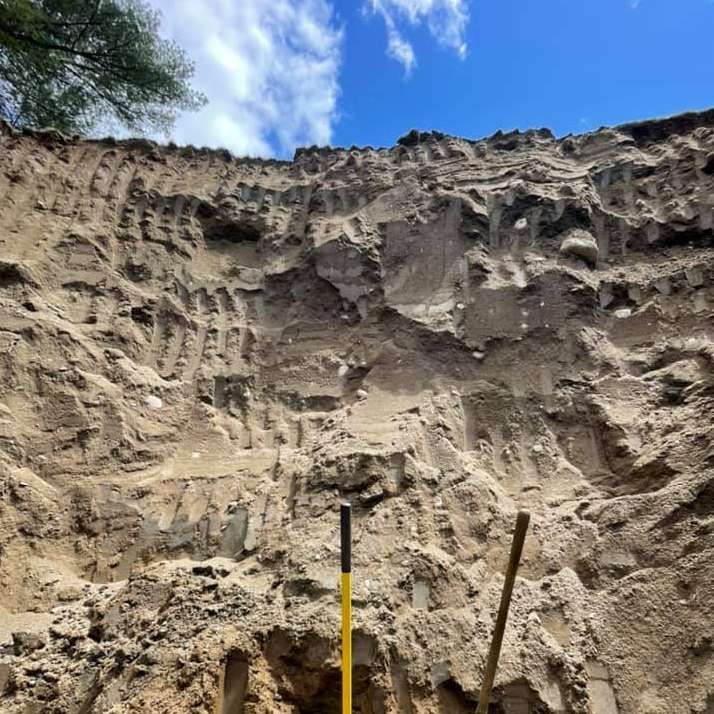 A shovel is sitting in the middle of a pile of dirt.