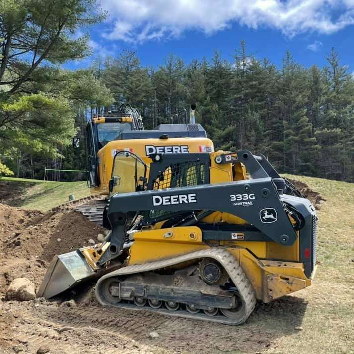 A deere bulldozer is sitting on top of a dirt field.