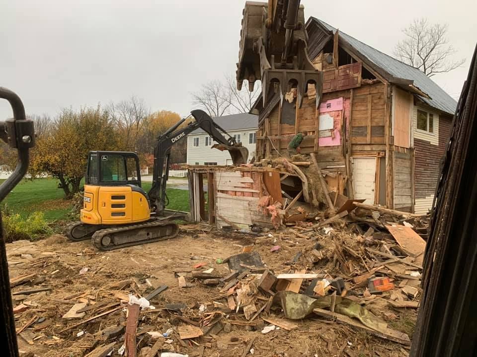 A yellow excavator is demolishing a house.