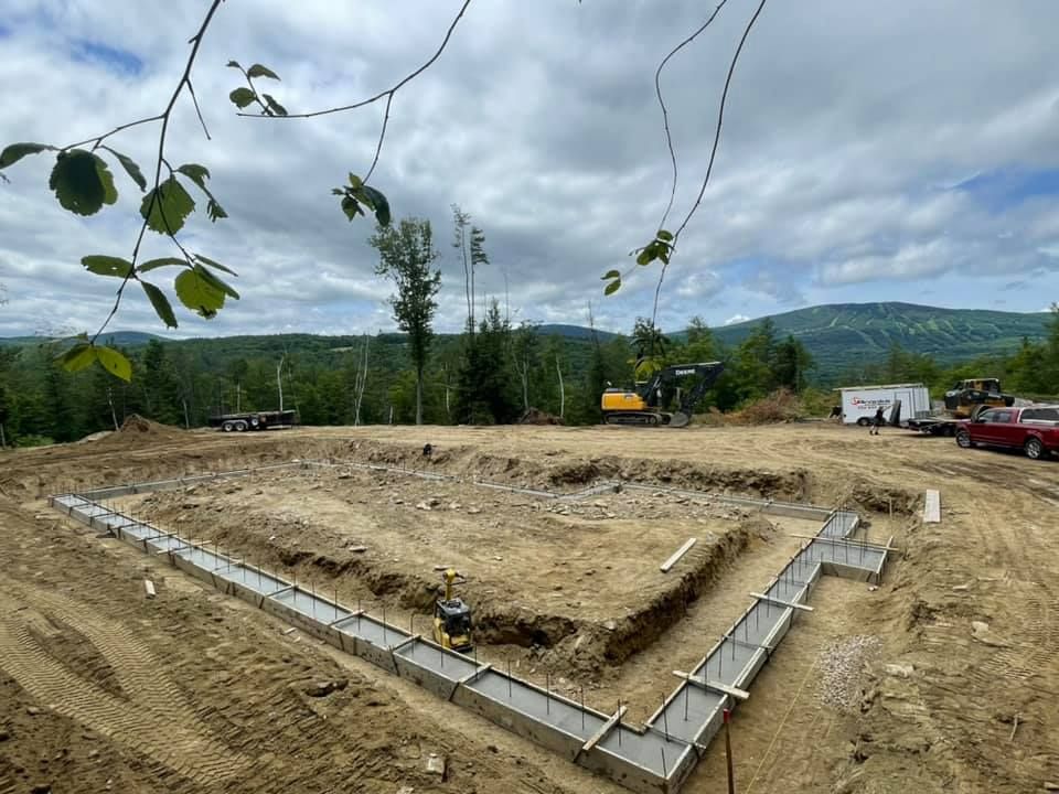 A construction site with a lot of dirt and trees in the background.
