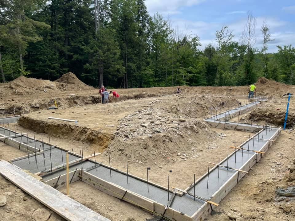 A construction site with a lot of dirt and trees in the background.