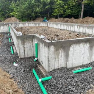 A concrete foundation for a house is being built with green pipes.