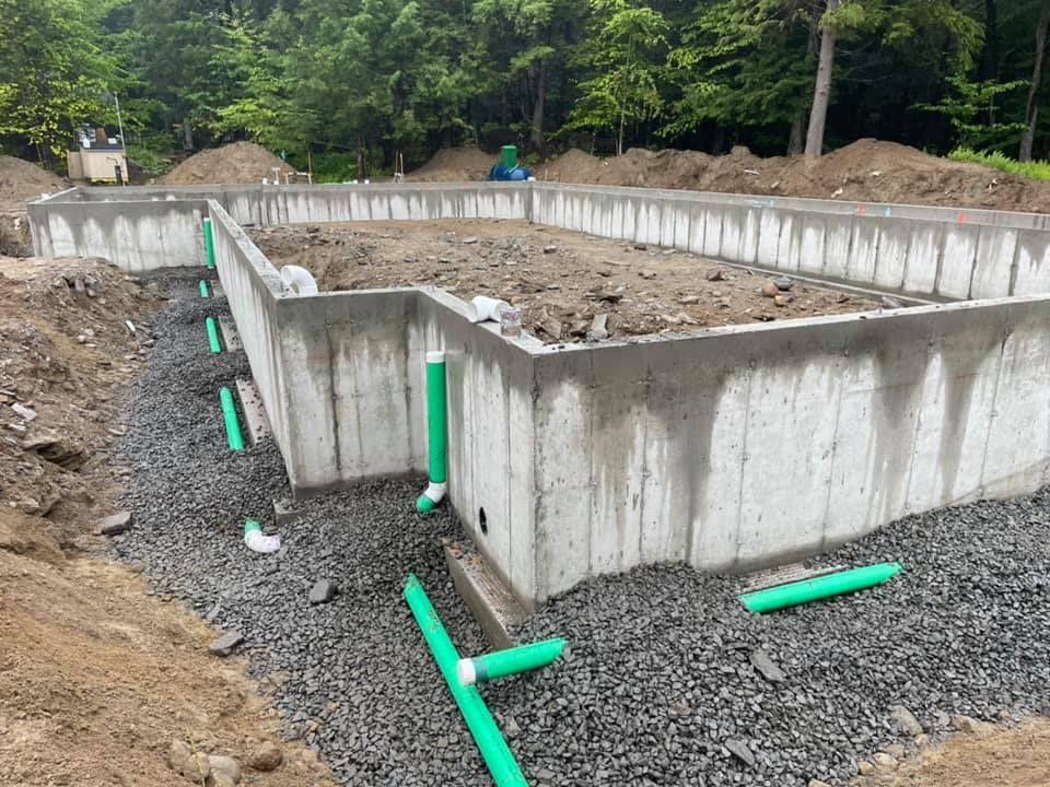 A concrete foundation for a house is being built with green pipes.