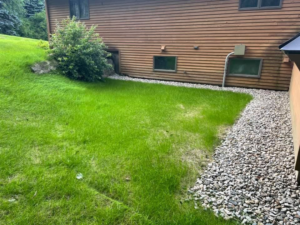 A house with a lot of grass and rocks in front of it.