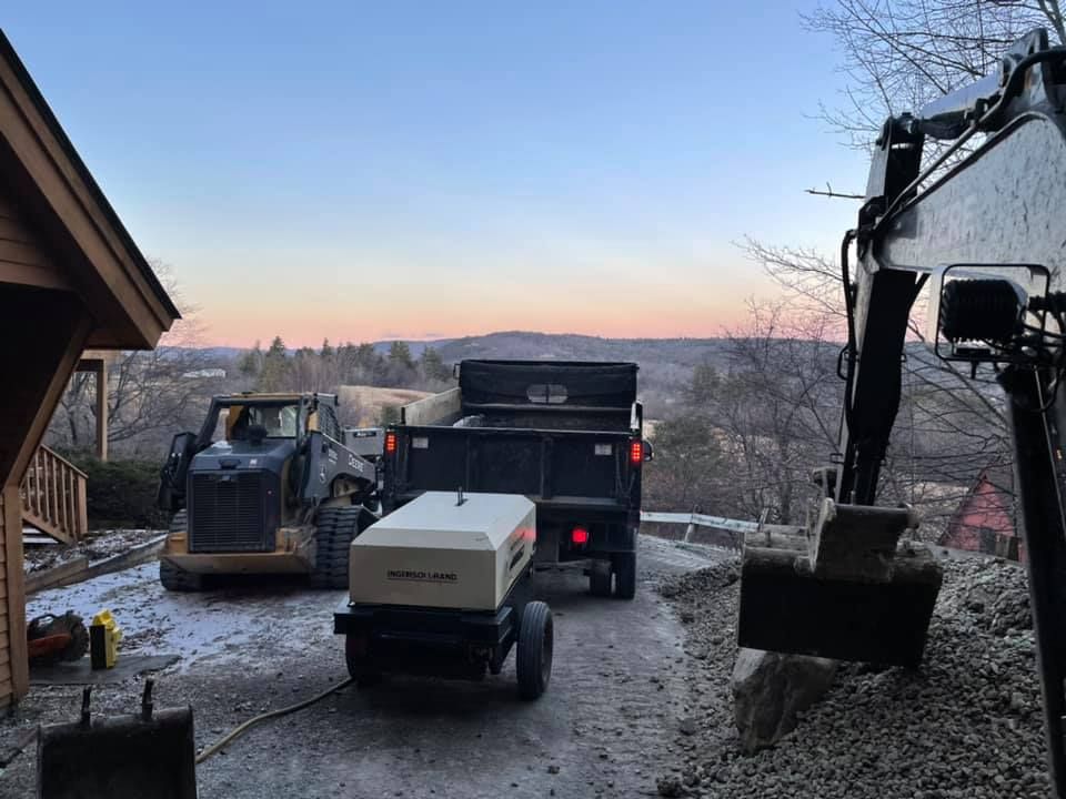 A dump truck is driving down a dirt road next to a tractor.
