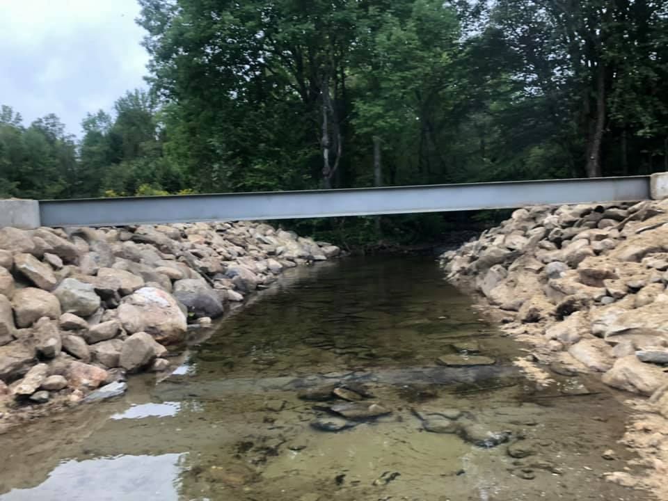 A bridge over a stream surrounded by rocks and trees.