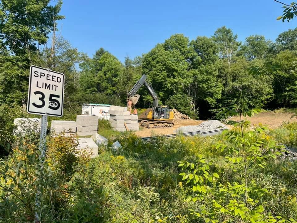 A speed limit sign is sitting in the middle of a field.