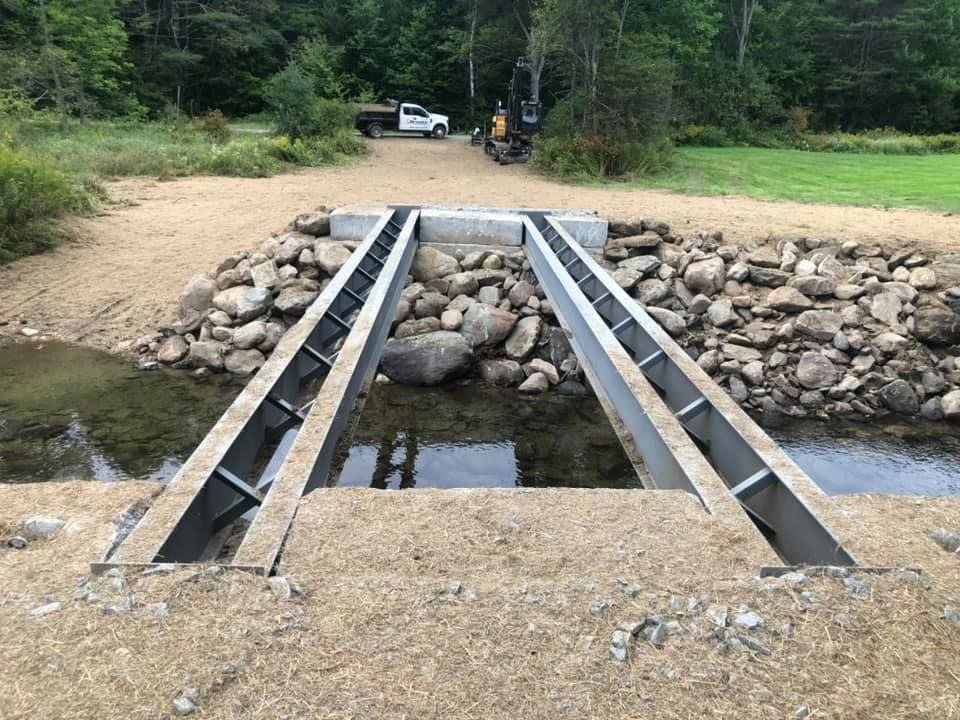 A bridge over a river with a truck parked in the background.