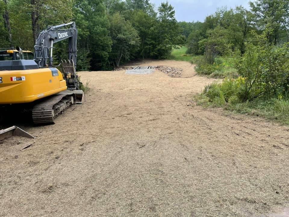A yellow excavator is sitting in the middle of a dirt field.