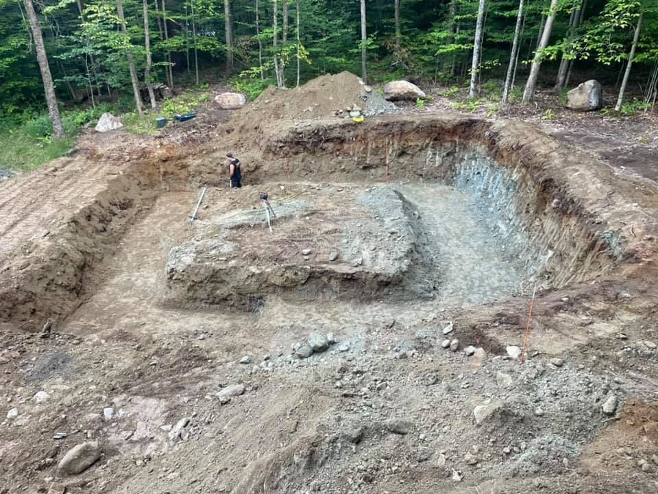 A large pile of dirt and rocks in the middle of a forest.