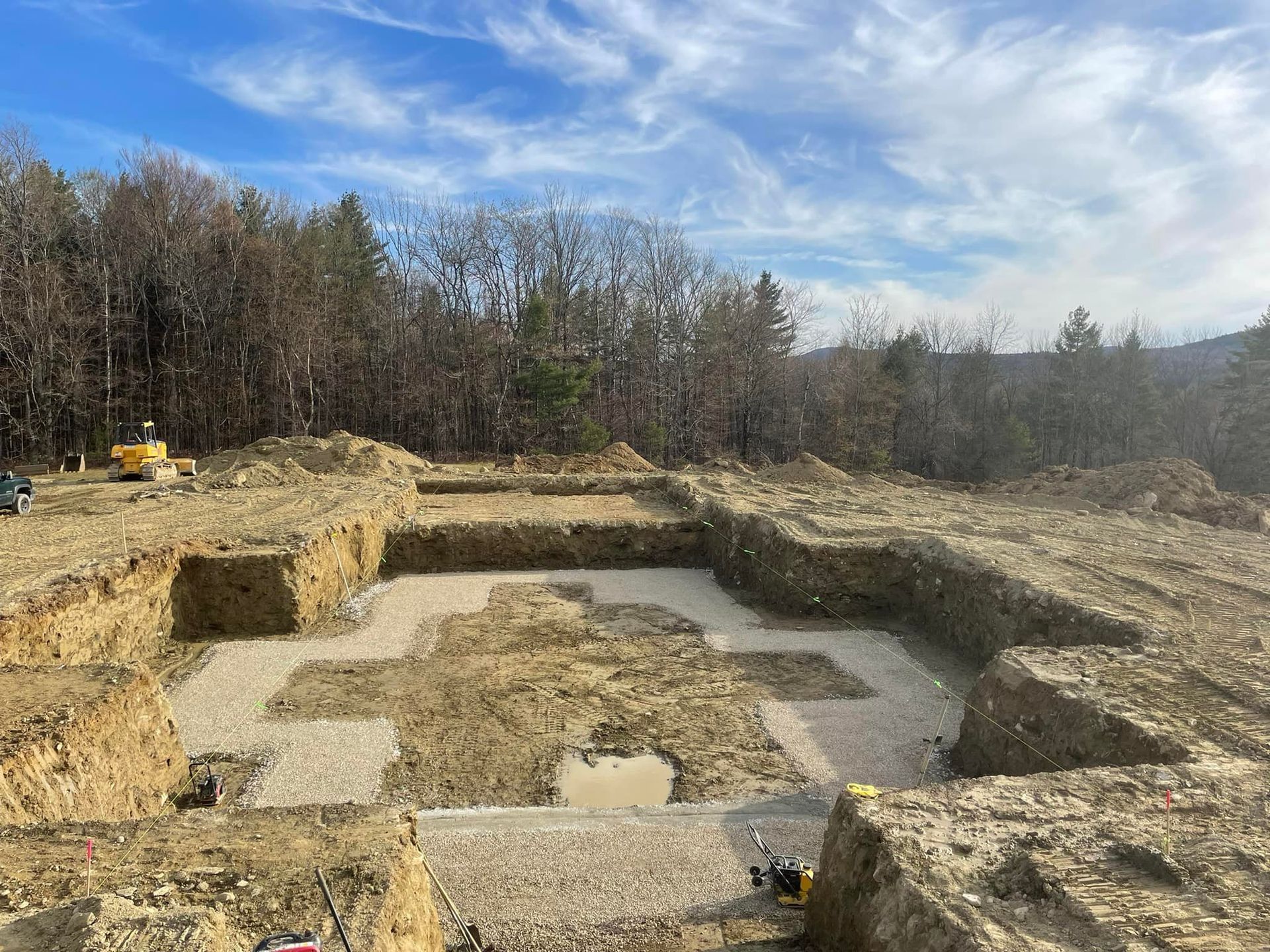 A construction site with a lot of dirt and trees in the background.