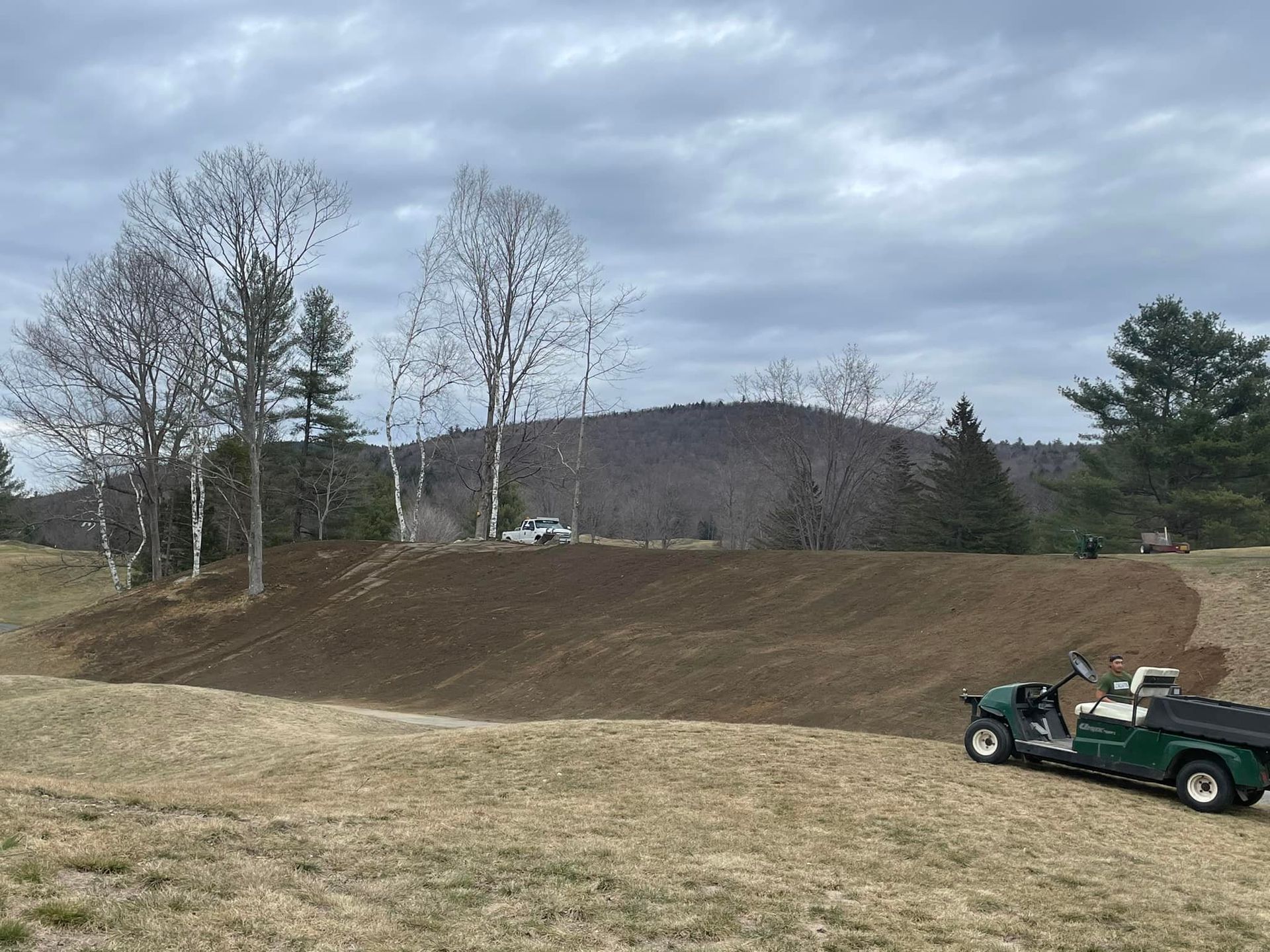A green golf cart is parked in the middle of a grassy field.