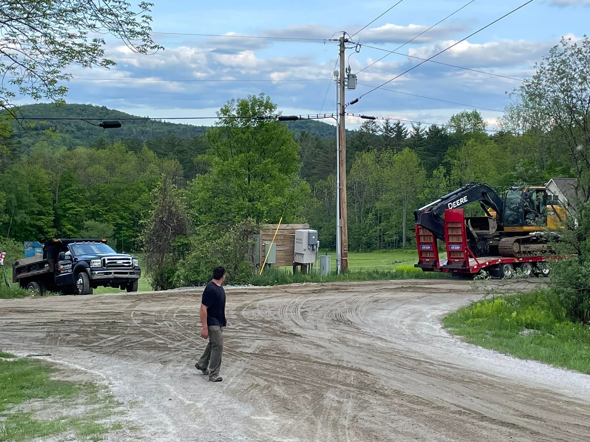 A man is standing on a dirt road next to a truck.