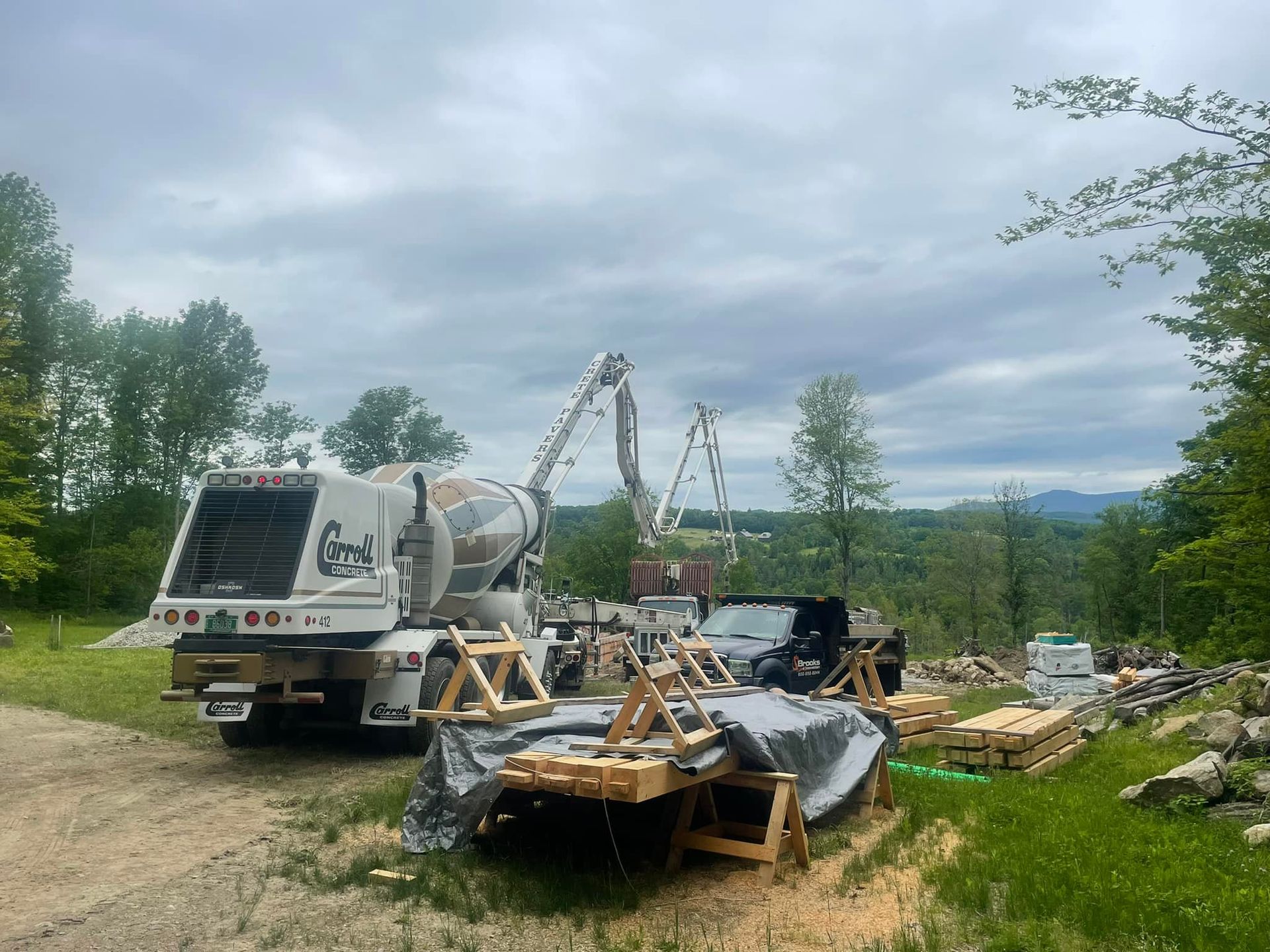 A concrete mixer truck is parked in a grassy field.