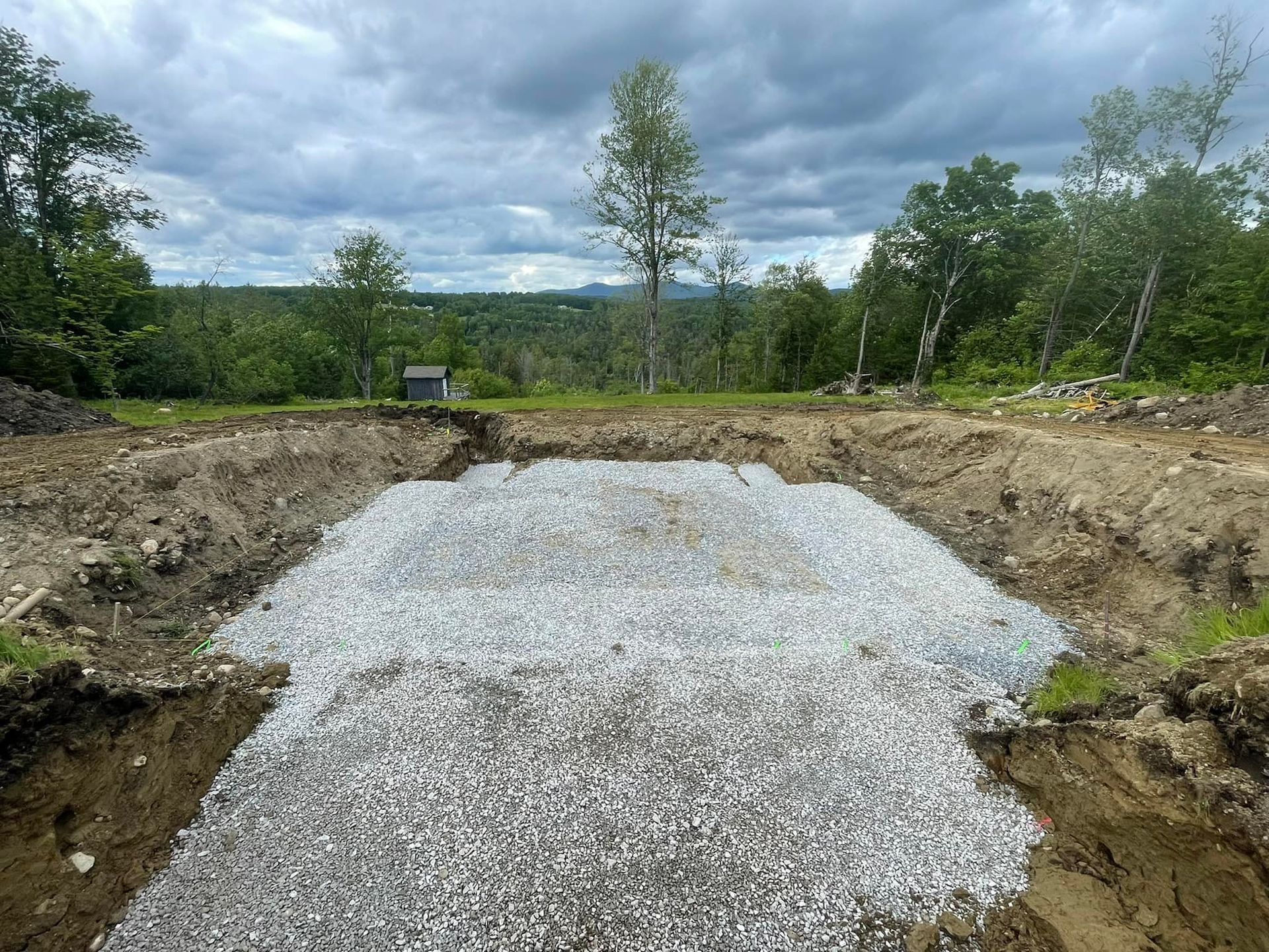 A large pile of gravel is sitting in the middle of a dirt field.