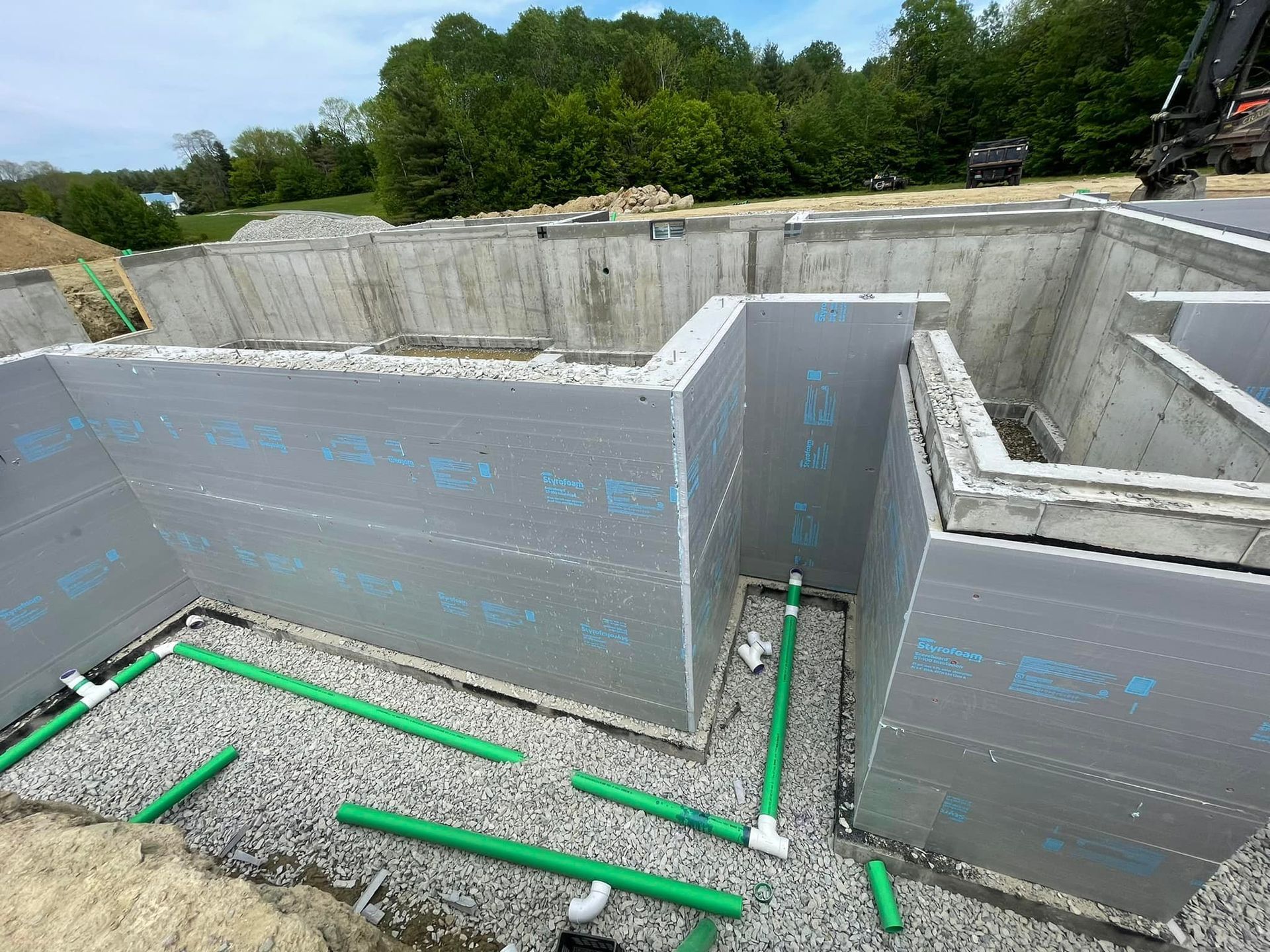 A concrete wall with green pipes going through it is being built.