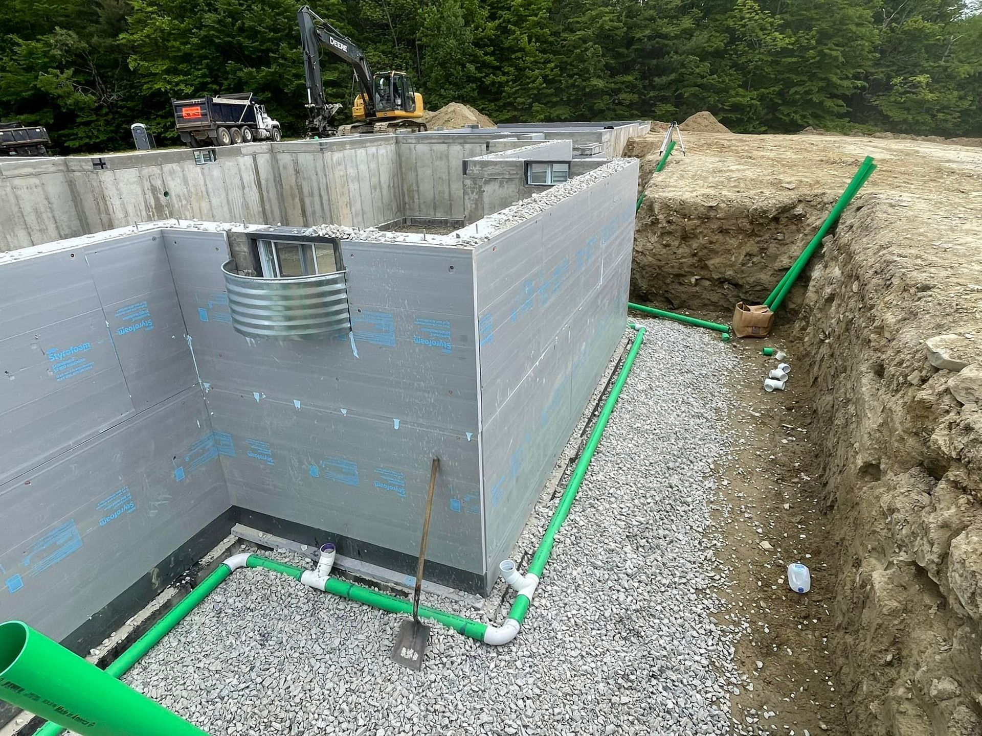 A construction site with a concrete wall and green pipes.