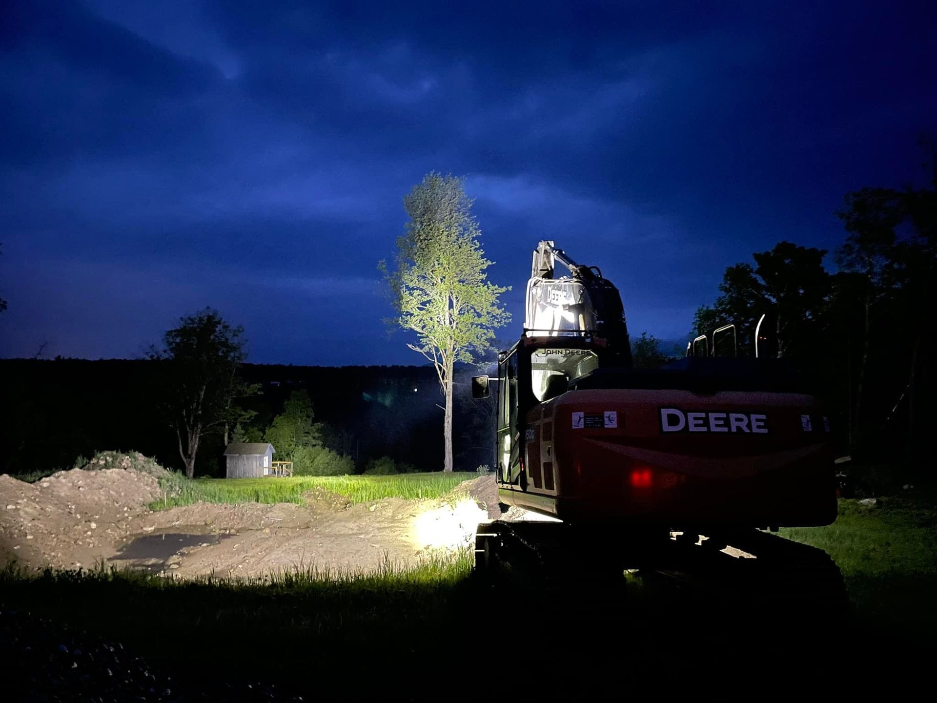 A deere excavator is working on a construction site at night