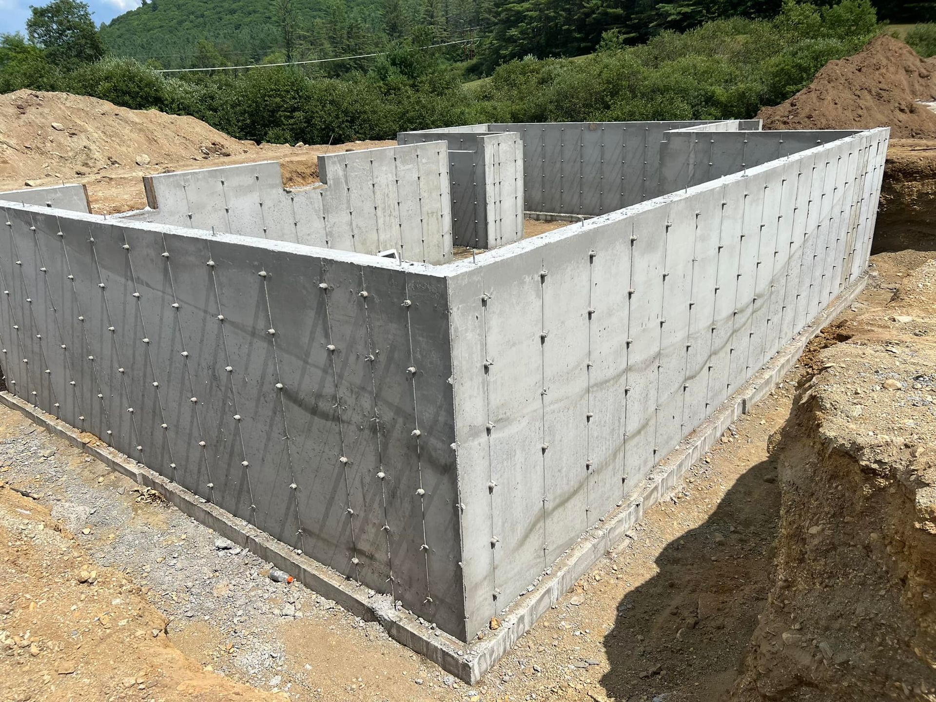 A large concrete wall is being built in a dirt field.