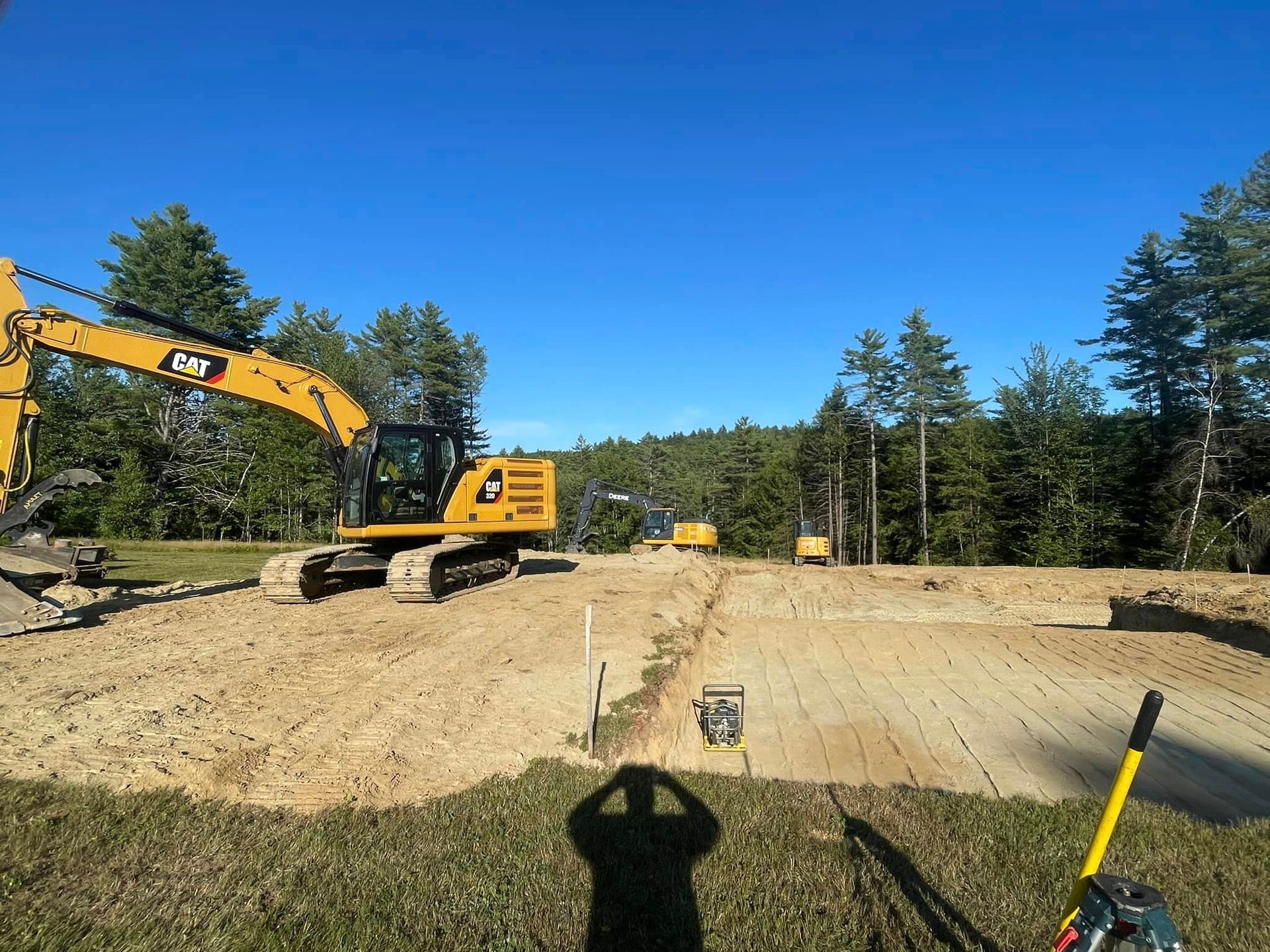 A large yellow excavator is sitting on top of a dirt field.
