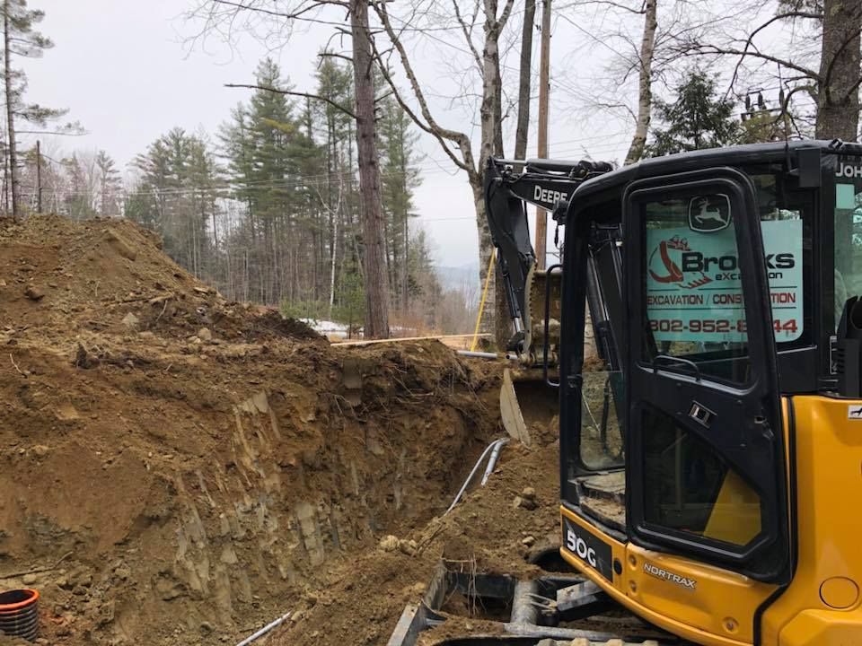A yellow and black excavator is digging a hole in the dirt.
