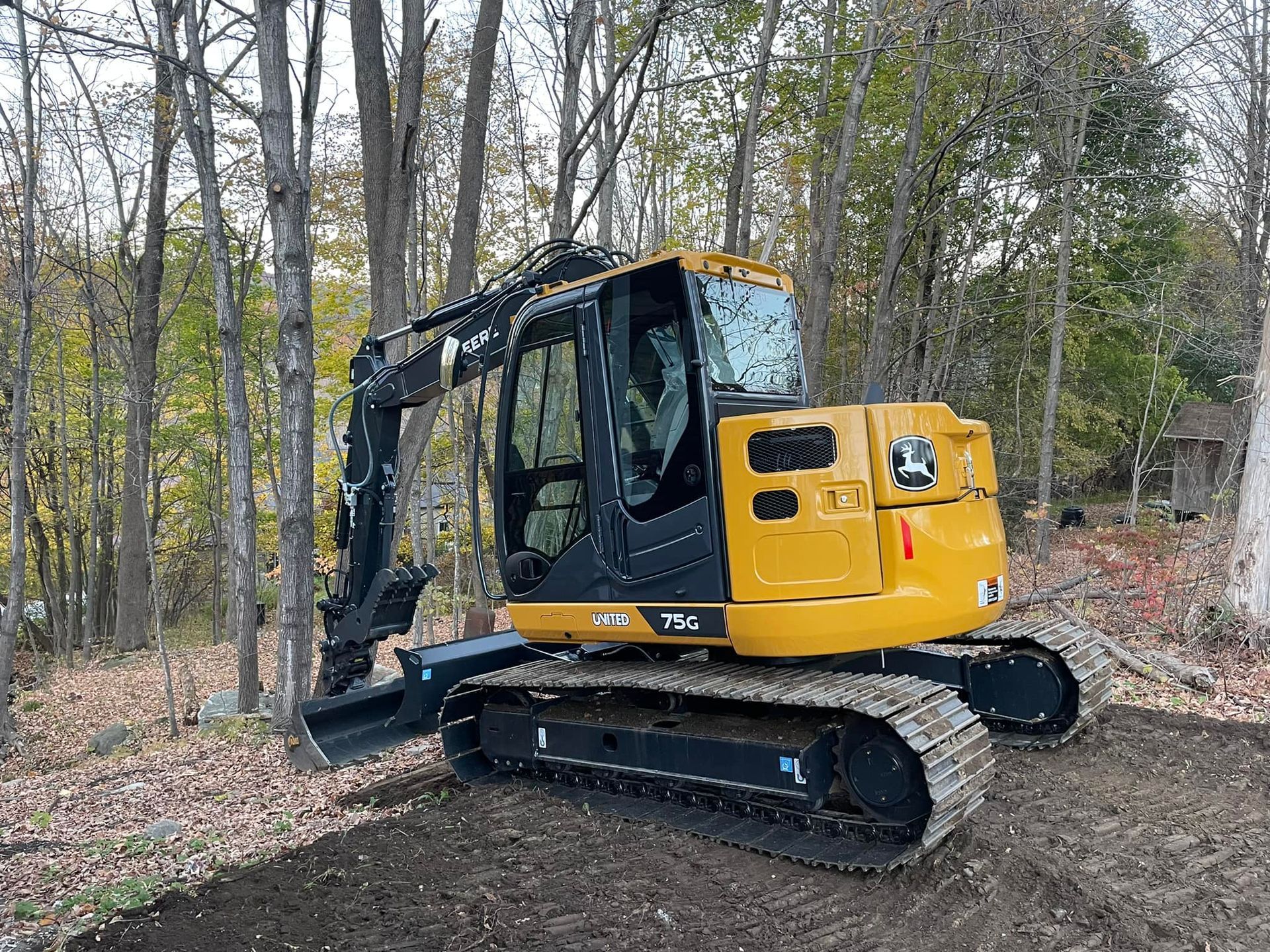 A yellow excavator is parked in the middle of a forest.