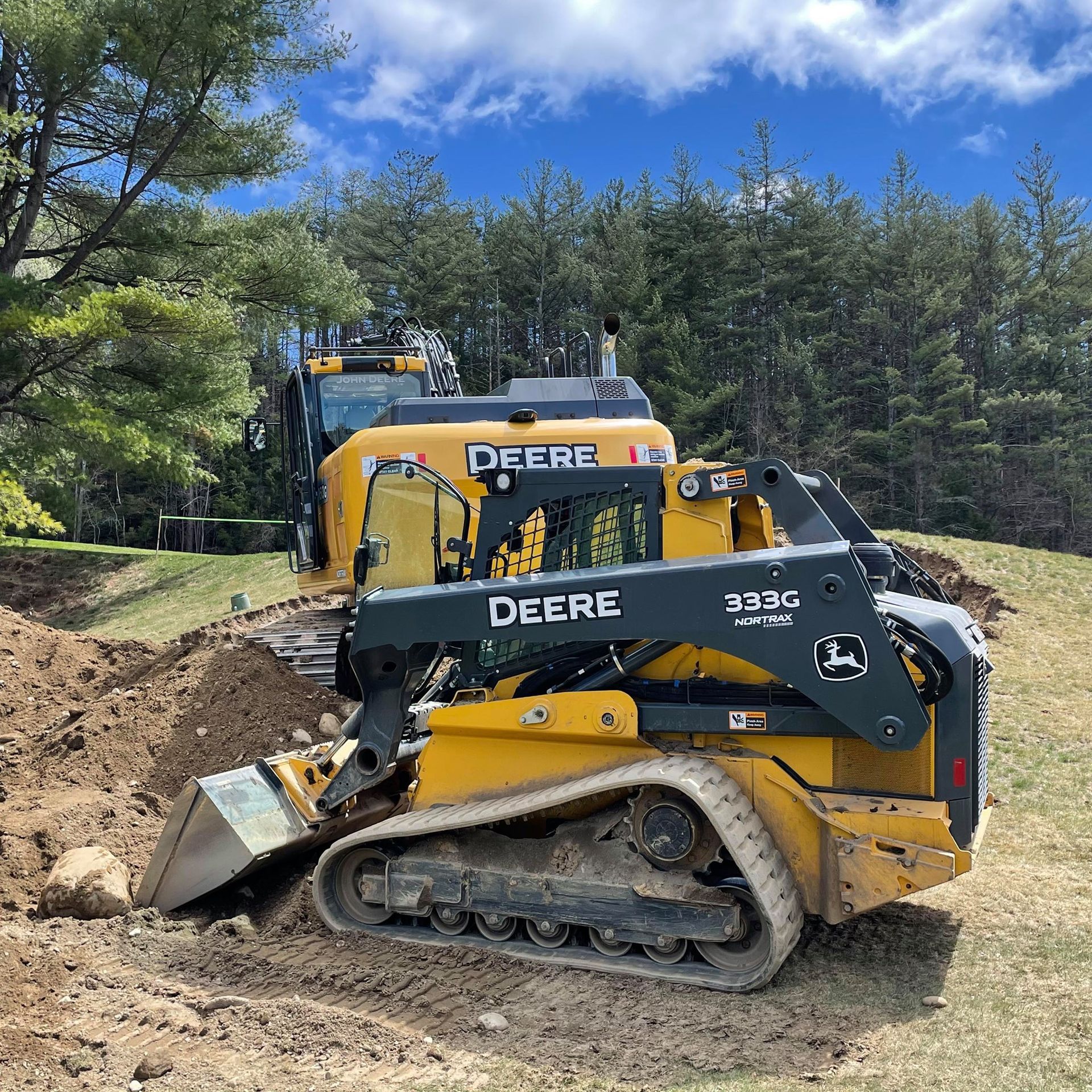A yellow and black deere bulldozer is sitting on top of a dirt field.