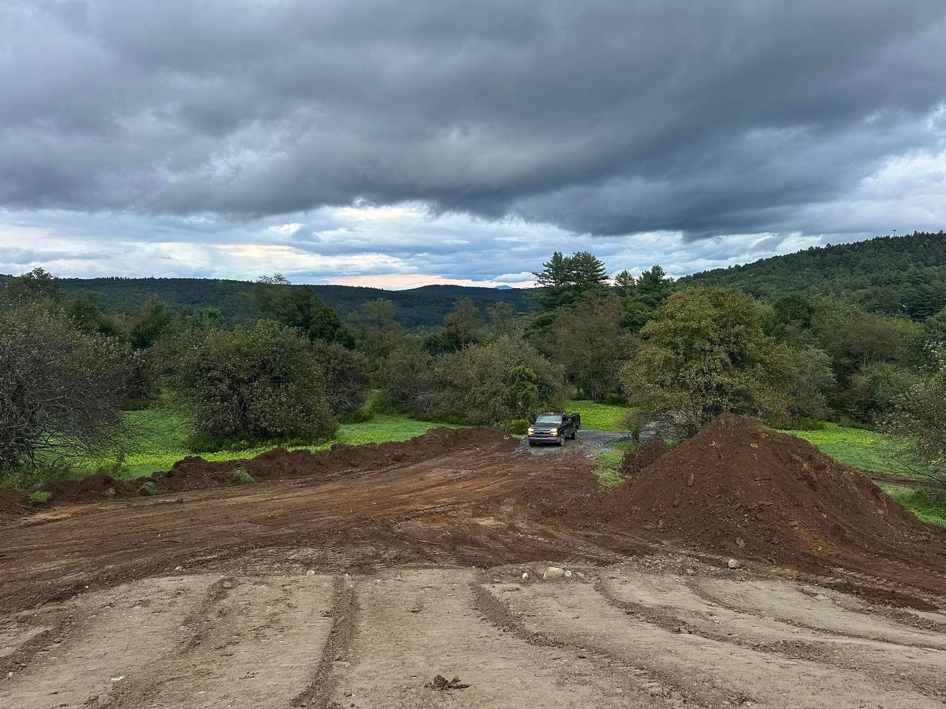 A car is driving down a dirt road next to a pile of dirt.