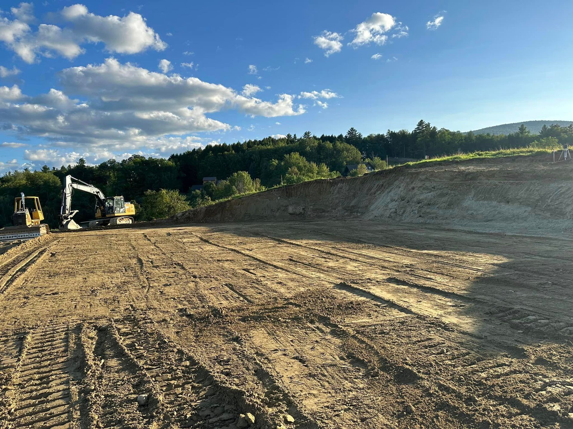 A construction site with a lot of dirt and trees in the background.