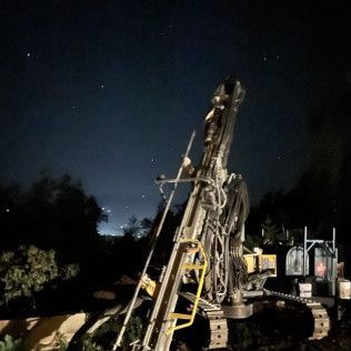 A large machine is sitting in the middle of a field at night.