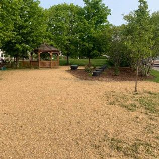 There is a gazebo in the middle of a park surrounded by trees.