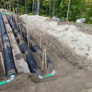 A bunch of pipes are sitting in the dirt on top of a hill.