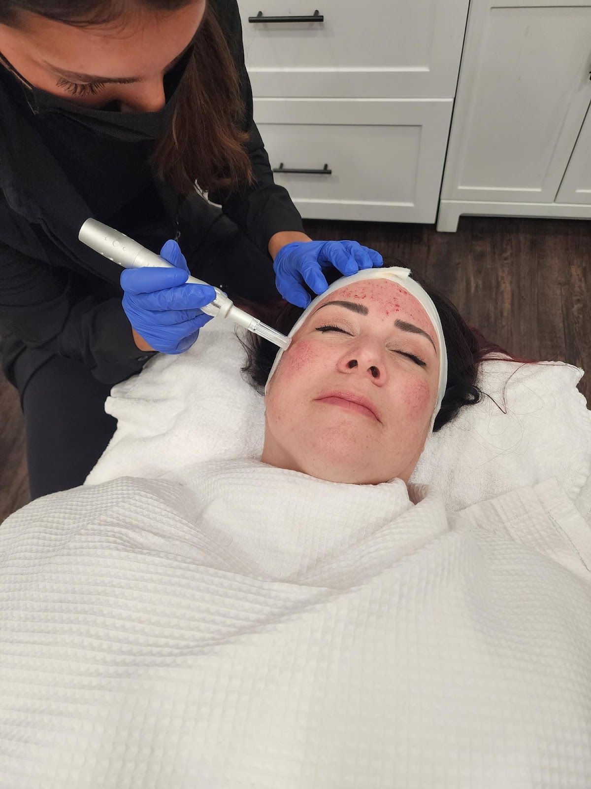 A woman is laying on a bed getting a facial treatment.