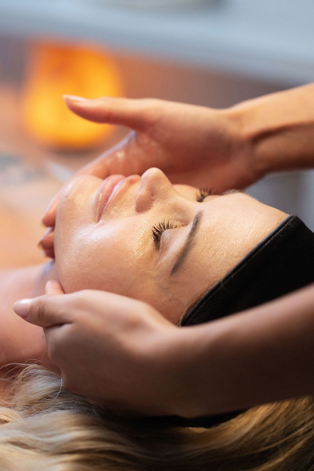 A woman is getting a facial massage at a spa.
