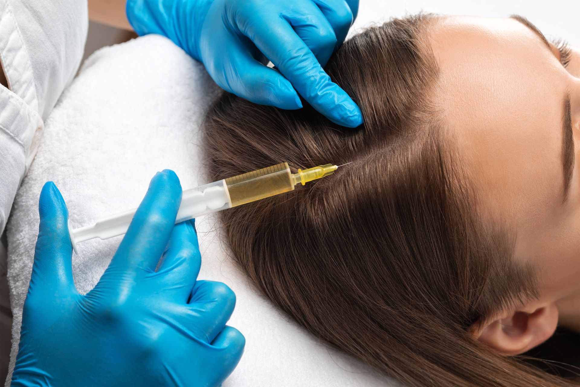 A woman is getting an injection in her hair.